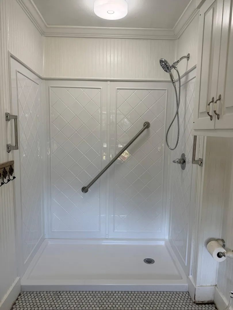Remodeled Houston shower with diagonal tile, hex floor tile and a grab bar