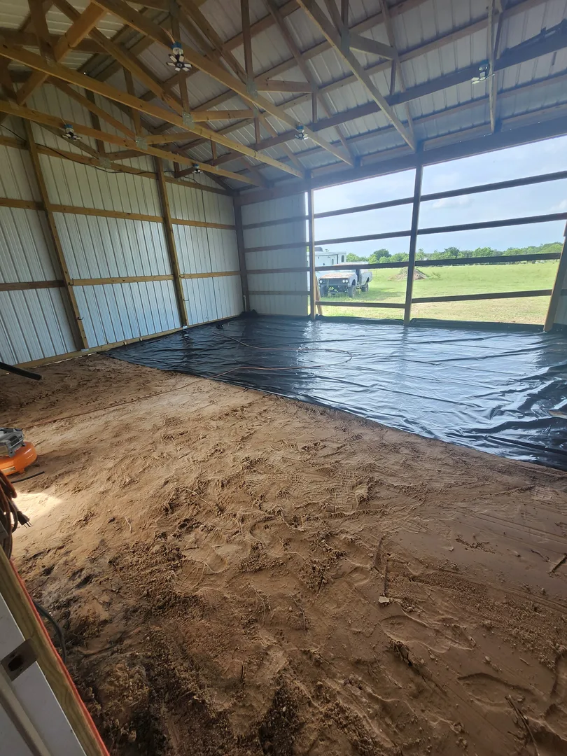 Vapor barrier and sand prep before a concrete pour inside a metal building near Houston, Texas